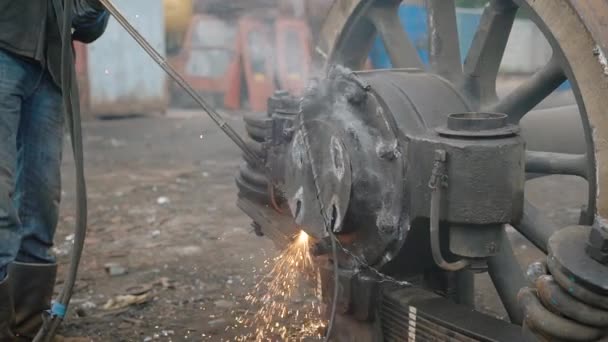 Крупним планом знімок промислового працівника, використовуючи ріжучий факел для розділення металевих частин коліс вантажівок . — стокове відео