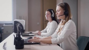 iki genç kadın çalışan bir çağrı merkezi ofis gündüz de üzerinde cevap kulaklıklar ve dizüstü bilgisayarlar kullanarak gelen