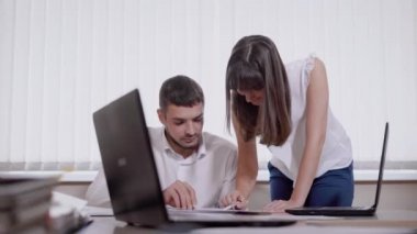 adam ofiste bir sandalyede oturuyor ve genç kadın yanında duruyor, her ikisi de bir tablo, yönetmen ve Yardımcısı bir kağıda arıyoruz