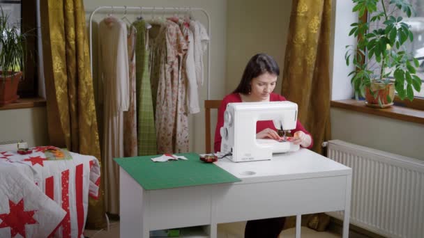 Una mujer trabaja para una máquina de coser en su taller de nebolshom, una dama hace vestidos, es diseñadora de ropa moderna — Vídeo de stock