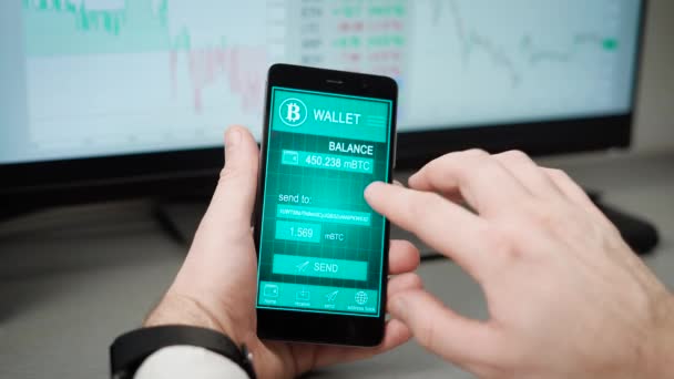 Il tizio in ufficio usa la sua borsa bitcoin sullo smartphone. Nel fotogramma delle mani al telefono, l'uomo invia i bitcoin a qualcuno indirizzo . — Video Stock