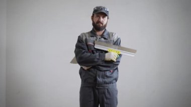 Sıvacı beyaz duvar arka plan daire üzerinde duran ve spatula ve büyük macun bıçak tutarak