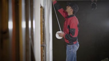 işçi işaretleri bir Alçıpan duvara, sabit, teyp, daire onarım sırasında yapıştırma yapar
