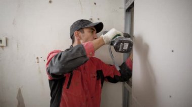 Yükleyici Alçıpan modül yapının vidalar bir duvar, bir bina nesne üzerinde bir çalışma günü içinde Akülü tornavida kullanarak büküm