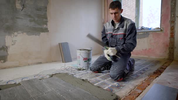 Maestro está instalando baldosas de cerámica de piso en una habitación, presionando hacia abajo y nivelación, acabado interior de los locales — Vídeo de stock