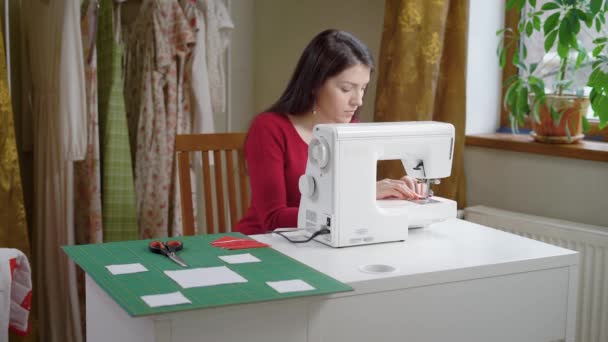 Mooie brunette vrouw is naaimachine aan te passen. — Stockvideo