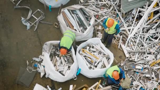 Bovenaanzicht van werknemers metalen vuilnis in grote zakken verpakken — Stockvideo