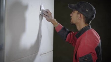 İnşaat işçisi duvara düz spatula ile tesviye.