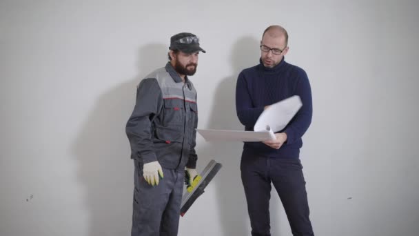 Construtor e seu chefe estão discutindo o plano de trabalho para o apartamento . — Vídeo de Stock