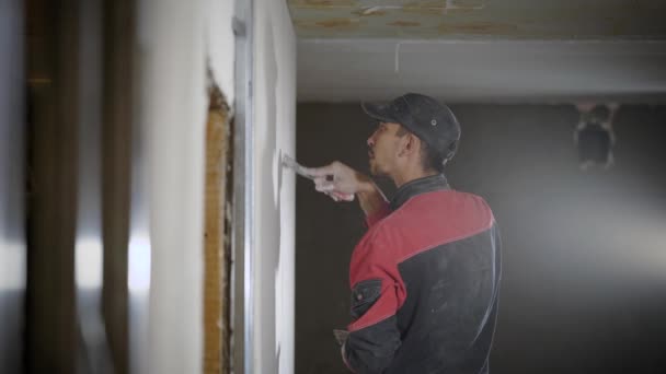 Bauarbeiter mit Spachtel renoviert Wohnungswände. — Stockvideo