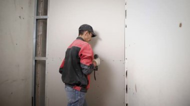 İnşaat işçisi üniforması dairede yeni drywall yükleme.