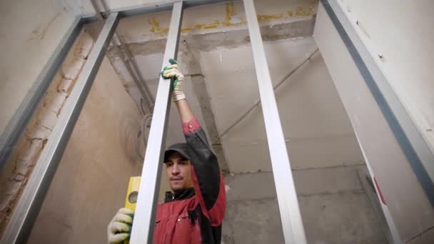 Робочий чоловік ретельно вирівнює профілі гіпсокартону використовуючи водяні паси . — стокове відео