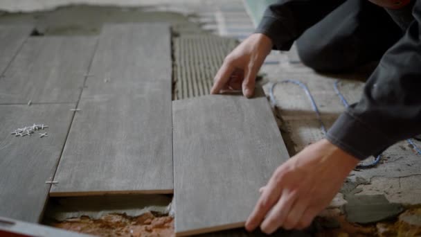 Close up shot of a construction worker laying ceramic tile on the levelled floor in the flat. — Stock Video