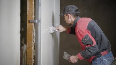 Bir spatula elinde tutuyor, duvarlara taşlarla kaplı bir harç geçerlidir profesyonel bir inşaatçı