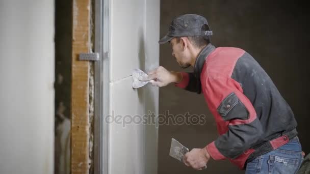 Un constructor profesional que sostiene una espátula en su mano, aplica una lechada en las paredes que están cubiertas con azulejos — Vídeos de Stock