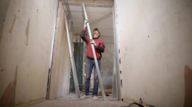 Sahte bir duvar eldiven Builder'da yükler, adam metal profilleri alçı karton duvar oluşturmak için kullanılır