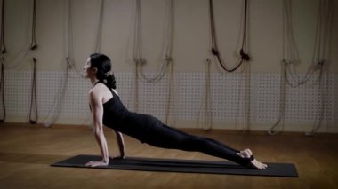 Esmer kadın fitness merkezinde yoga yapıyor. O pozlar mindere değişiyor.