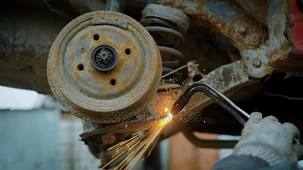 Primer plano de un trabajador utiliza una antorcha de corte para cortar un objeto metálico grande en pedazos en una planta de reciclaje de metales — Vídeos de Stock