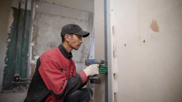 Человек с помощью инструмента крепления перекрытия на стене в здании — стоковое видео