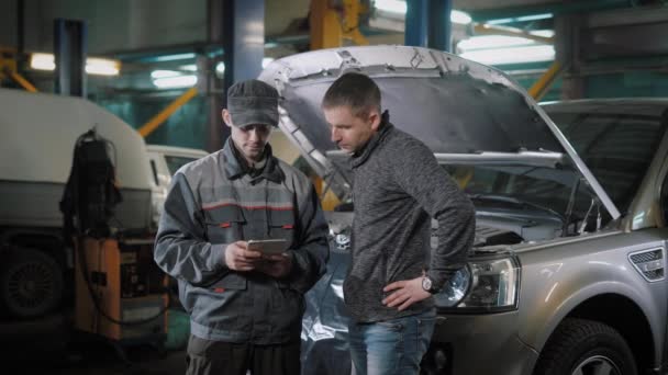Zwei Männer unterhalten sich in Autowerkstatt — Stockvideo