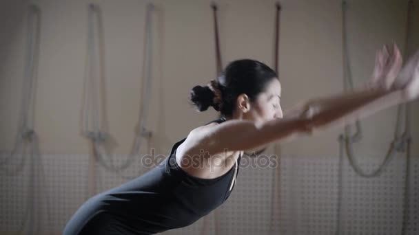 Une jeune femme en costume de sport, effectue des exercices de flexibilité, une dame engagée dans le yoga sur le tapis — Video