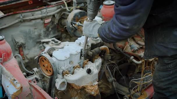 リサイクルのためのさびた車のエンジンからボルトを引っ張る人タイヤのチェンジャーの手のショットを閉じる — ストック動画