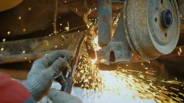 Close up shot of the tire changer hands, who uses the Bulgarian in order to utilize the details of a rusty machine, sparks fly from the instrument — Stock Video