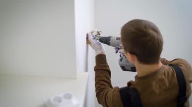 Elektrik teknisyen soket bir mekanizma beyaz bir duvar teller Akülü tornavida kullanarak bağlandığı