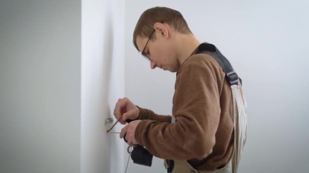 電気技師は改装されたアパートで新しい壁にインストールするための壁ランプにワイヤを接続します。 — ストック動画
