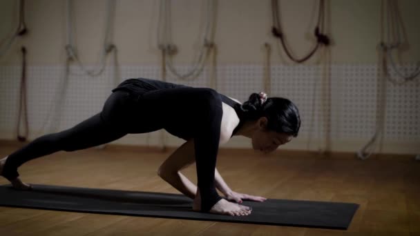 体操运动员妇女是舒展她的腿在一个健身室在地板席子和制作杂技元素 — 图库视频影像