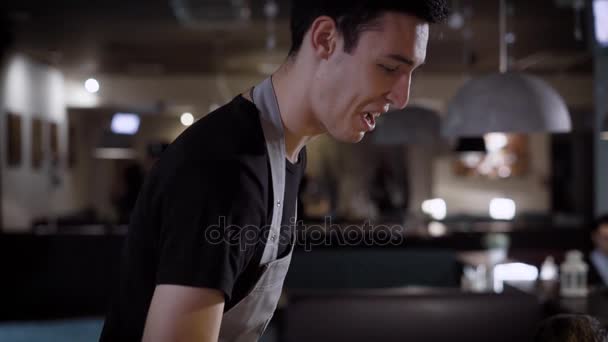 Un serveur amical et souriant conseille aux clients du restaurant plats pour le dîner, dans un lieu public bon service — Video