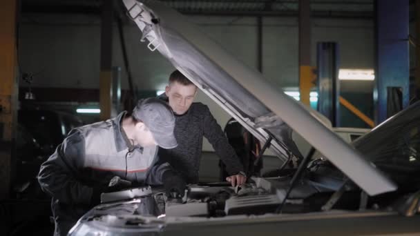 Master is het controleren van vloeistoffen in een auto, covers van reservoirs draaien, auto-eigenaar is permanent in de buurt van en de controle — Stockvideo