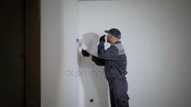 bir inşaat Tekdüzen boyalar duvarları dairede bir genç adam, builder bir rulo çalışır.