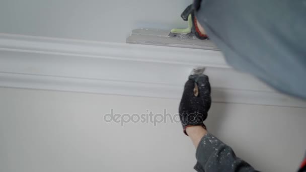 Cerca de tiro a un constructor manos, un hombre haciendo reparaciones en un apartamento, la gente pintar un pincel con una moldura en el techo — Vídeos de Stock