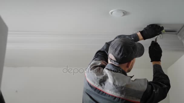 L'uomo sta facendo le riparazioni in appartamento, la persona sta dipingendo con un intonaco nappa stampaggio sul soffitto — Video Stock