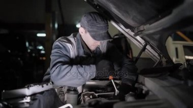 Bir araç bir anahtar yardımı ile onarmak için bir profesyonel araba tamir teknisyeni çalışır, o kapağın detayları unscrews