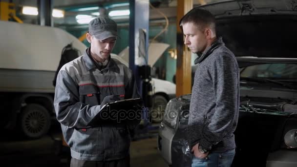 L'homme adulte s'est tourné vers le service de la machine pour réparer sa minifourgonnette, le conducteur parle au réparateur — Video