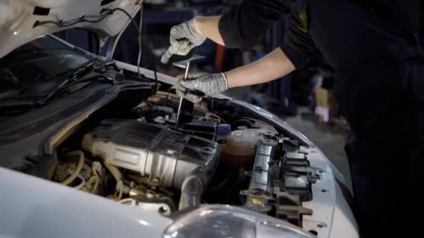 Gros plan d'un mécanicien examinant le véhicule sous le capot dans le garage . — Video