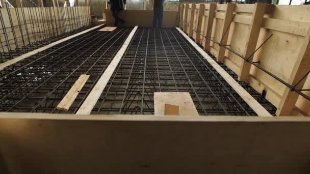 Arbeiter stehen und gehen an Werktagen auf einer Baustelle über die Bodenplatte des Käfigs — Stockvideo