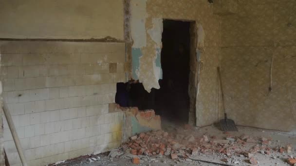 Construtor está quebrando uma parede no velho apartamento, golpeando com uma marreta em um canteiro de obras, tijolos estão espalhando — Vídeo de Stock