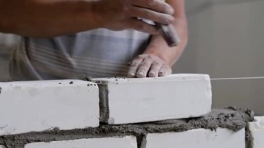 Builder tuğla yapıyor, tesviye ve bir aşırı çimento harç alarak mala tarafından üzerinde tuğla isabet