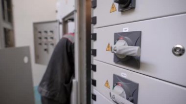 Elektrikçi elektrik dağıtım panosu, kolları ile kapalı geçiş panoları içinde büyük bir endüstriyel çalışıyor