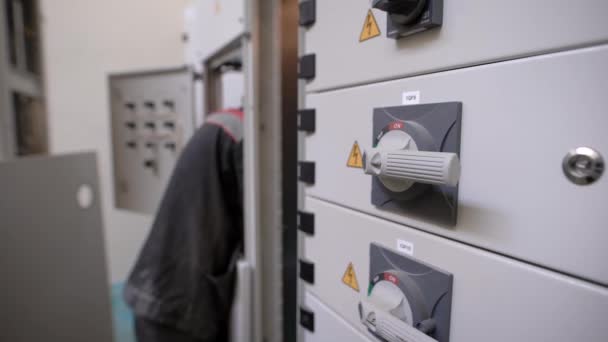 Electricista está trabajando dentro de un gran industrial una placa de distribución eléctrica, cuadros de distribución cerrados con asas — Vídeo de stock