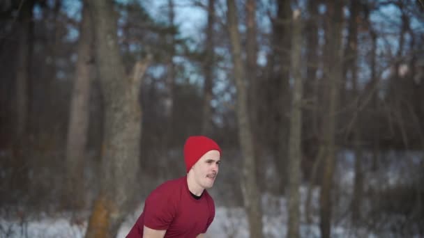 Halterci giymiş kırmızı şapka yükselen ve ağır kettlebell bir ormanda kış günü içinde bırakarak. — Stok video