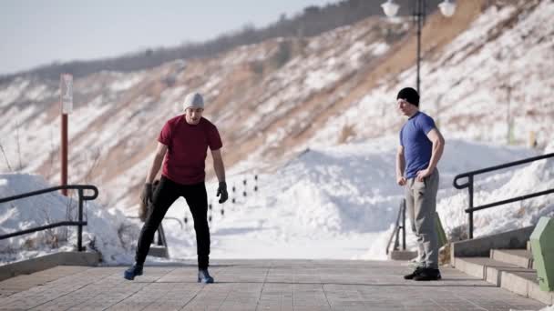Young breakdancer is doing a trick, standing to hand and jumping with a turnovers outdoors in winter day — Stock Video