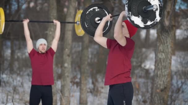 Two sportsmen doing crossfit in a winter forest together. — Stock Video