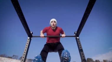 Genç güçlü athlet çekme işi ups kış doğada çubuğunda.