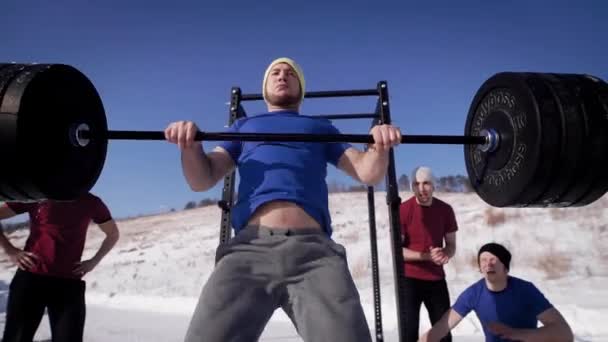 Skott från nedan av en stor kille som tränar med en skivstång utomhus på vintern. — Stockvideo
