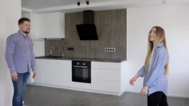 genç adam ve kadın yeni evlerinin, gülümseyerek ve birbirlerine mutfakta kucaklayan tadını çıkarıyor