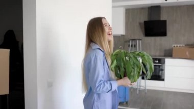 Genç neşeli kadın elinde çiçek ile yeni dairede giriyor ve kocası özellikleri ile büyük bir kutu taşıyor